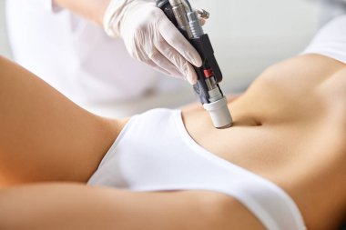 Profesyonel güzellik kliniğinde randevusu sırasında karın bölgesinden lazer tedavisi gören kimliği belirsiz kadın hasta.