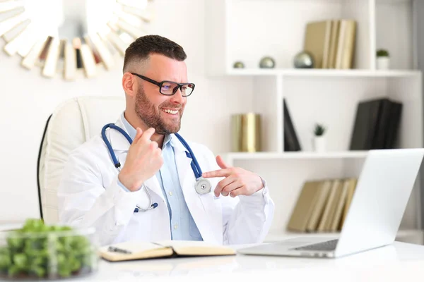 Pozytywny Człowiek Lekarz Stetoskopem Ramionach Okularach Patrząc Ekran Laptopa Zapewniając — Zdjęcie stockowe