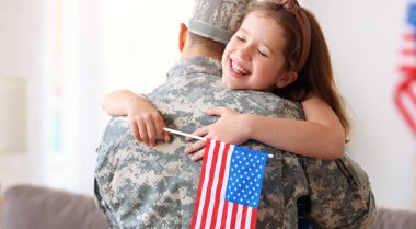 Amerikan bayrağı taşıyan mutlu küçük bir kız çocuğu askeri üniformalı babasına sarılıyor, Amerikan ordusundan geri döndü, babasının dikiz aynasından erkek asker evde ailesiyle bir araya geldi.