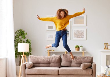Özgürlüğün tadını çıkarıyorum. Neşeli genç Afro-Amerikan kadınlarıyla dolu, günlük kıyafetleriyle salonda dans eden, zıplayan ve zıplayan, mutlu melez genç kızlar evde tek başına eğlenerek vakit geçiriyorlar.