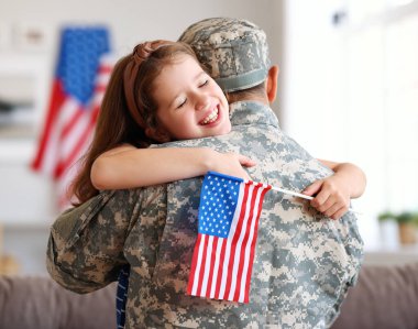 Amerikan bayrağı taşıyan mutlu küçük bir kız çocuğu askeri üniformalı babasına sarılıyor, Amerikan ordusundan geri döndü, babasının dikiz aynasından erkek asker evde ailesiyle bir araya geldi.