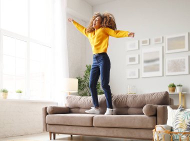 Özgürlüğün tadını çıkarıyorum. Neşeli genç Afro-Amerikan kadınlarıyla dolu, günlük kıyafetleriyle salonda dans eden, zıplayan ve zıplayan, mutlu melez genç kızlar evde tek başına eğlenerek vakit geçiriyorlar.