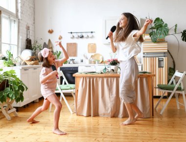 Aileyle çılgın bir hafta sonu. Küçük, mutlu bir kızı olan genç bir kadın anne mikrofon olarak saç fırçalarını tutuyor, karaoke söylüyor ve evdeki modern, rahat mutfakta dans ediyor.