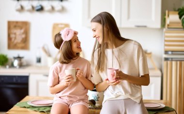 Annemle iyi vakit geçirdim. Genç, sevimli anne ve tatlı küçük kız çay içip gülümserken modern, rahat bir mutfakta, büyük ve küçük kız kardeş evde aile hafta sonunun keyfini çıkarıyorlar.