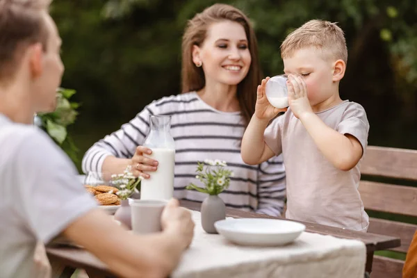 在花园里享受大自然的家庭早餐 一个夏日的早晨 快乐的妈妈和小儿子和爸爸在餐桌边喝牛奶 吃新鲜的饼干 — 图库照片