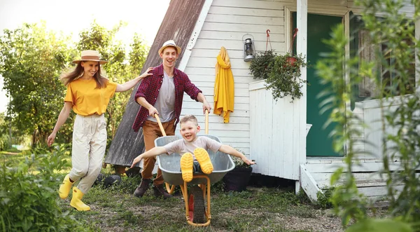 Happy Mother Son Outstretched Arms Smiling Riding Wheelbarrow Father Cottage — Stock Photo, Image