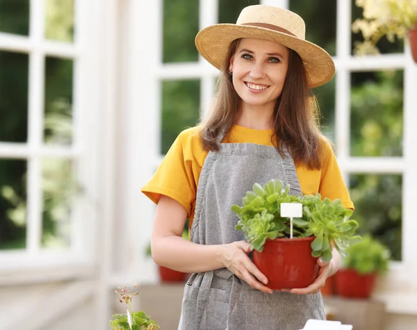 カメラで笑顔と庭で夏の日に光のオレンジで鉢植えの植物の世話をする幸せな女性庭師 — ストック写真