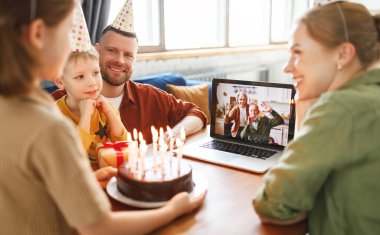 Olumlu son sınıf çifti parti şapkası takıyor. Küçük kızı internetten kutluyorlar. Kameraya el sallıyorlar ve düdük çalıyorlar.
