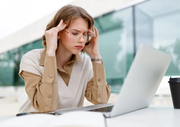 疲惫不堪的年轻女企业家闭目养神 满脸痛苦的手指按摩庙宇 坐在笔记本电脑前 在网上远程办公 开放议程 — 图库照片