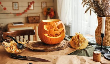 Klasik oymacılık Jack-o-Lantern, büyük, ağzı açık sırıtış, üçgen gözler ve mutfak ahşap masa üzerinde duran burun, seçici odaklanma. Cadılar Bayramı balkabağı dekorasyonu konsepti