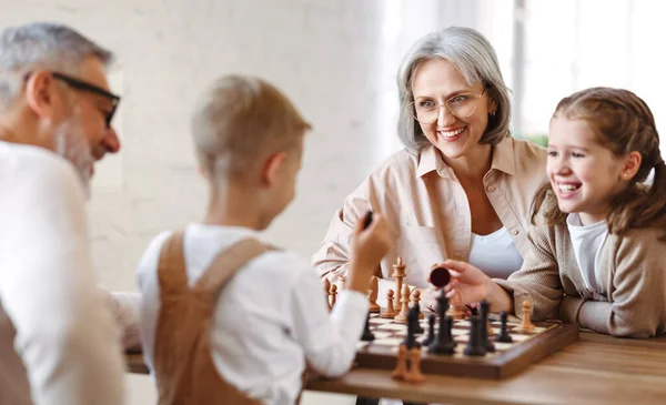 주말에 시간을 보내는 노부모와 거실에 체스를 즐거움을 자녀들 미소를 어린이들 — 스톡 사진