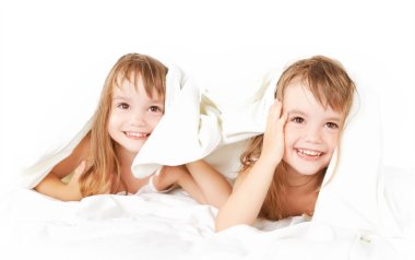 mutlu küçük kız ikiz kardeş eğleniyor battaniyenin altında yatakta