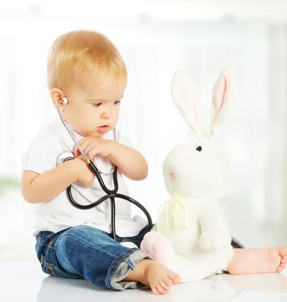 Bebê joga no coelho brinquedo médico coelho e estetoscópio — Fotografia de Stock