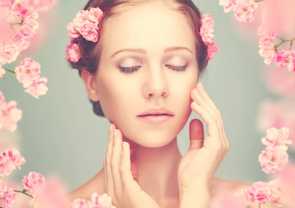 Schoonheid gezicht van jonge mooie vrouw met roze bloemen — Stockfoto