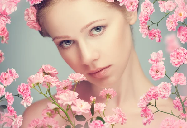 Schoonheid gezicht van jonge mooie vrouw met roze bloemen — Stockfoto