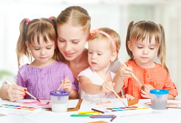 Children twin sisters draw paints with her mother in kindergarten — Stock Photo, Image