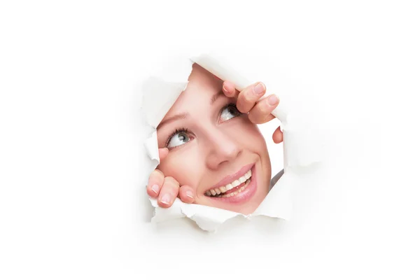 Rosto de mulher espreitando através de um buraco rasgado em cartaz de papel branco — Fotografia de Stock