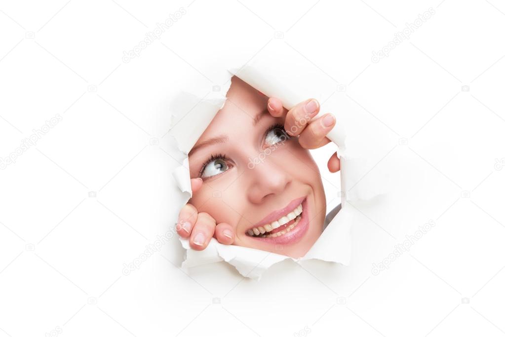 face of  woman peeking through a  hole torn in white paper poster