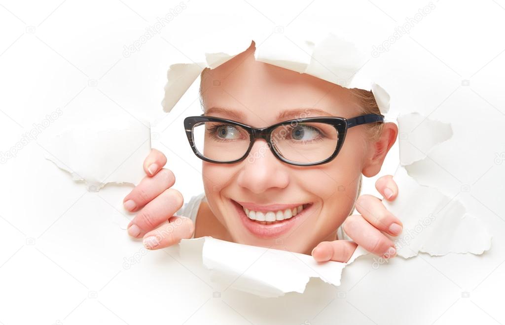face of  woman in glasses peeking through a  hole torn in white paper poster