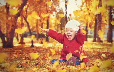 mutlu küçük bir çocuk, gülen ve sonbaharda oynayan kız bebek