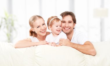 Mutlu aile anne, baba, çocuk bebek kızı evde oynarken ve gülerek Divan
