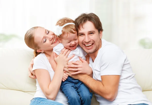 Feliz familia madre, padre, hija bebé en casa en el sofá jugando y riendo —  Fotos de Stock