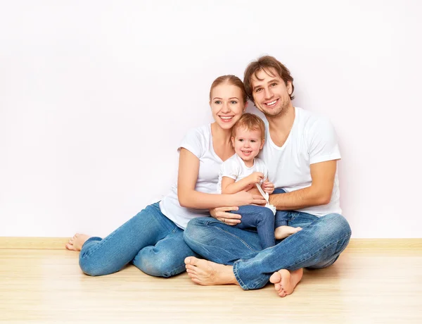 Familia feliz en el piso cerca de la pared vacía en el apartamento comprado en la hipoteca —  Fotos de Stock