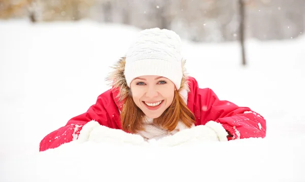 Feliz chica ríe mientras está acostado en la nieve en invierno al aire libre —  Fotos de Stock