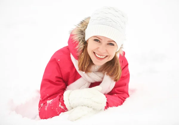 Happy girl laughs while lying on the snow in  winter outdoors Stock Photo