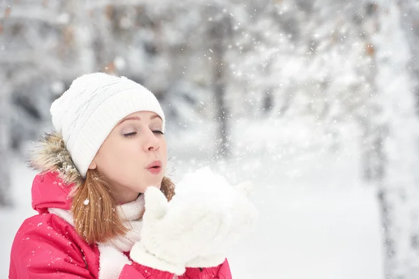 Happy girl on a frosty winter walk on street blows snow from hands — Stock Photo, Image