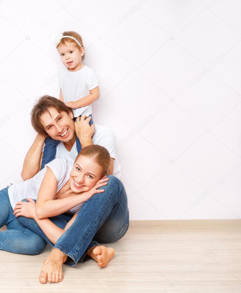 Happy family on  floor near  empty  wall in the apartment bought on mortgage
