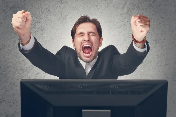 Emotional young businesman rejoices win at the computer — Stock Photo, Image