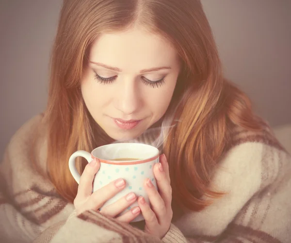 Menina feliz está sob um cobertor e xícara de café na manhã de inverno em casa — Fotografia de Stock