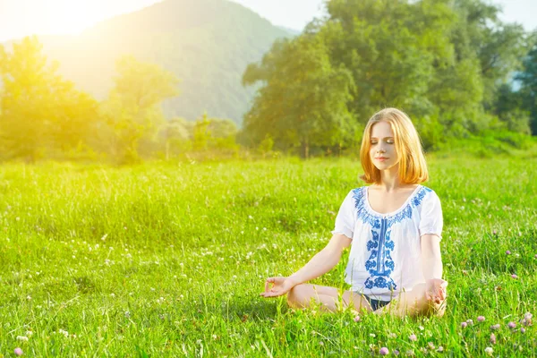 做瑜伽在绿色草地上的年轻女子 — 图库照片