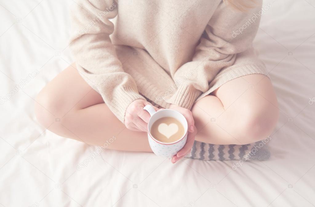legs of girl warm woolen socks and  cup of coffee warming, winter morning in bed