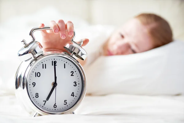 Wekker en slapende jonge vrouw — Stockfoto