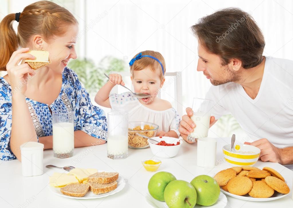 Happy family mother, father, child baby daughter having breakfas