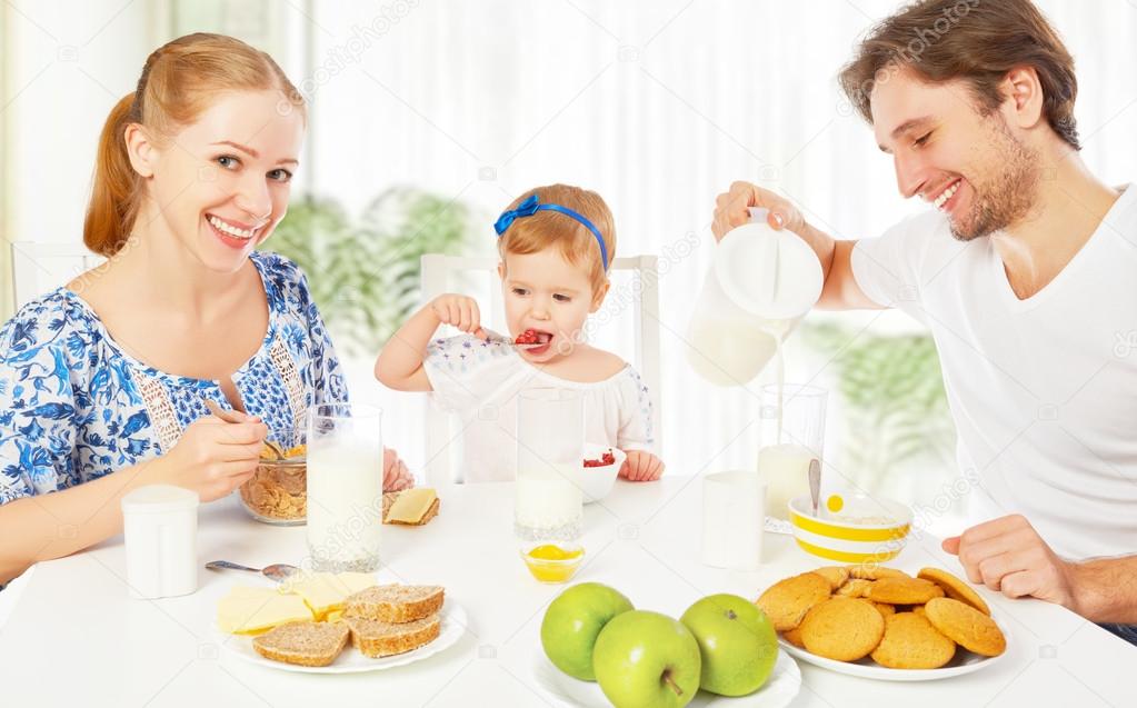 Happy family mother father child baby daughter having breakfas