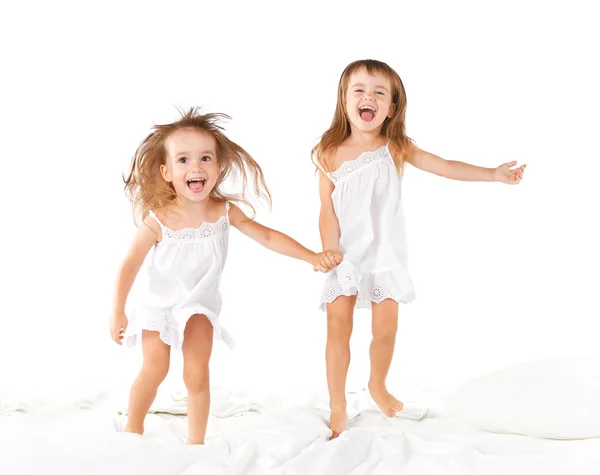 Gelukkige familie. kinderen tweelingzusjes springen op het bed, spelen een — Stockfoto