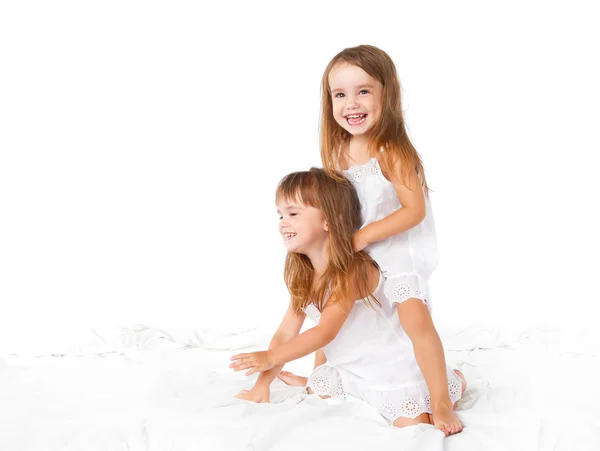 Família feliz. crianças irmãs gêmeas pulando na cama, jogando um — Fotografia de Stock