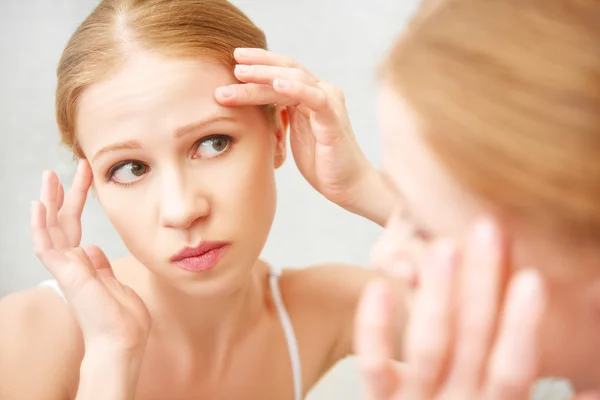 Mooie gezonde vrouw bang zag in de spiegel acne en w — Stockfoto