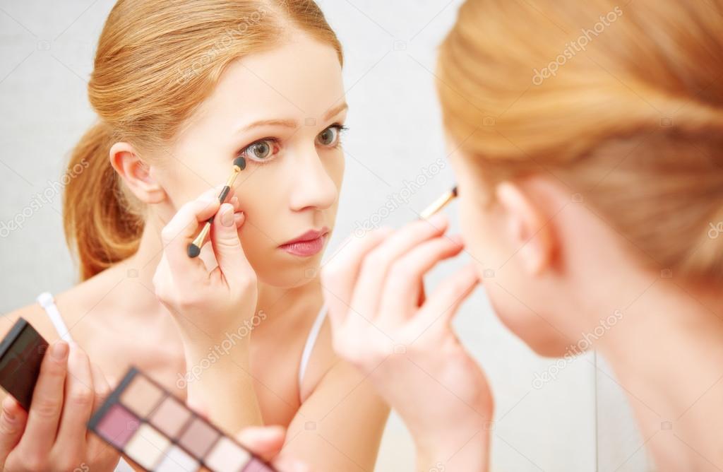 young beautiful woman apply makeup eyeshadow front of  mirror