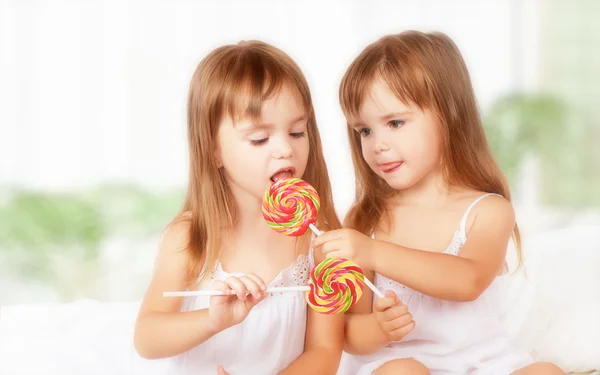 Menina feliz irmãs gêmeas com pirulitos doces — Fotografia de Stock