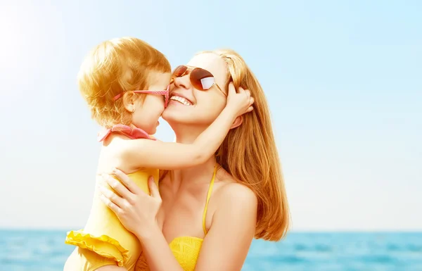 Happy family on beach. baby daughter kissing mother — Stock Photo, Image