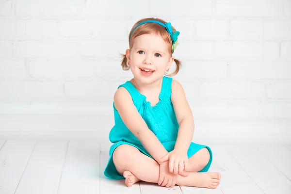 Mooie kleine babymeisje in een turquoise jurk — Stockfoto