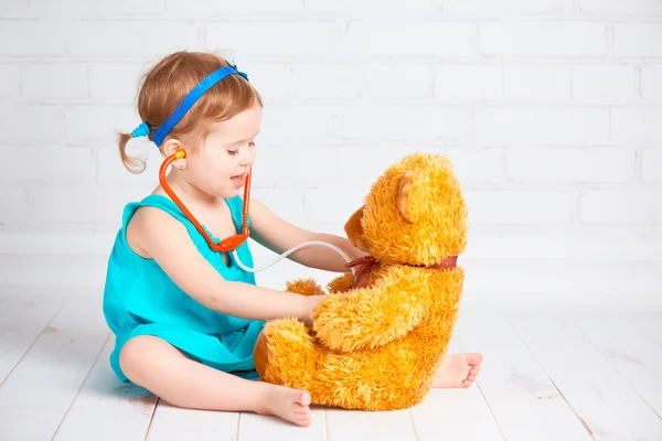 Girl playing doctor and treats teddy bear Royalty Free Stock Photos