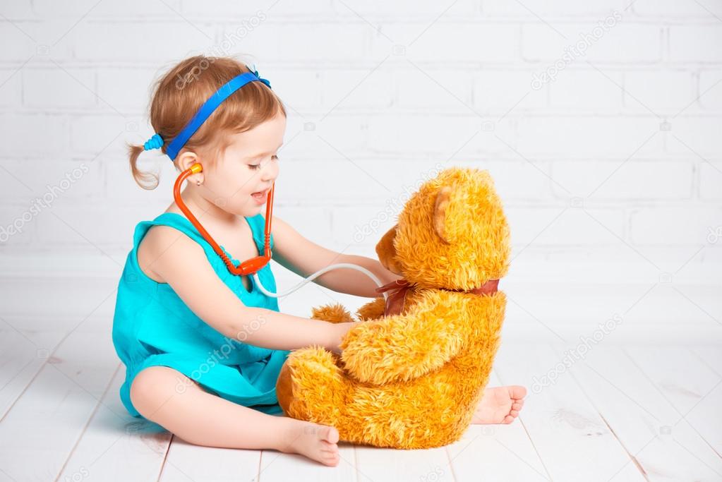 girl playing doctor and treats teddy bear