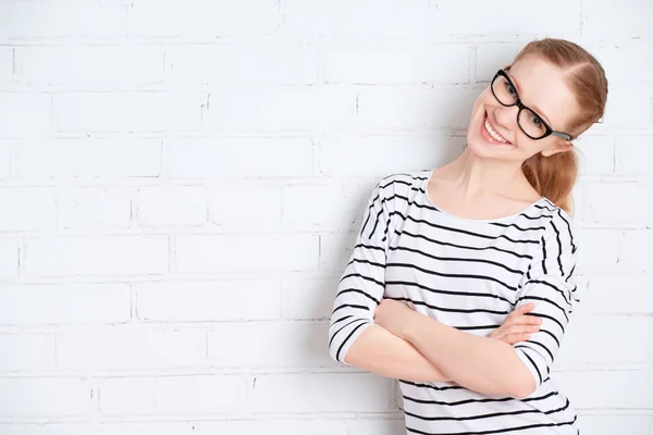 Šťastná dívka student v brýlích na prázdné bílé cihlová zeď — Stock fotografie
