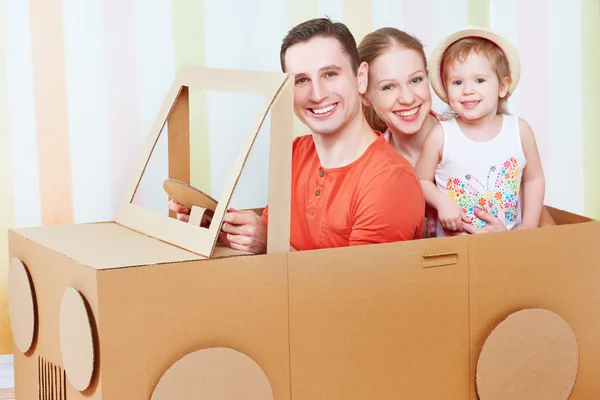 Happy family mother, father, daughter ride on toy car made of ca