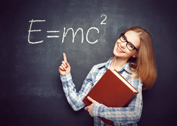 Feliz estudiante chica con libro y gafas ha escrito en blackbo —  Fotos de Stock